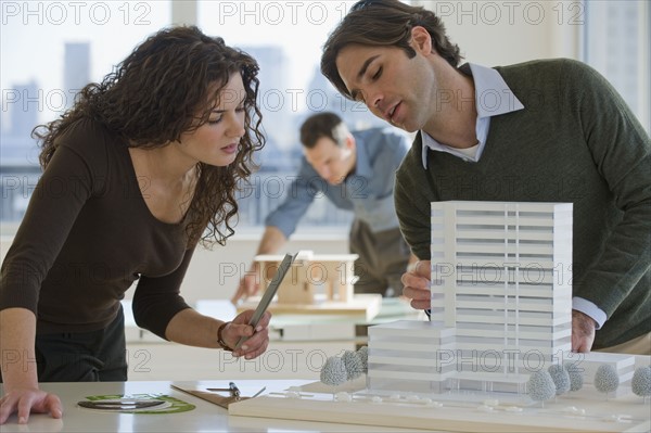 Architects constructing building model.