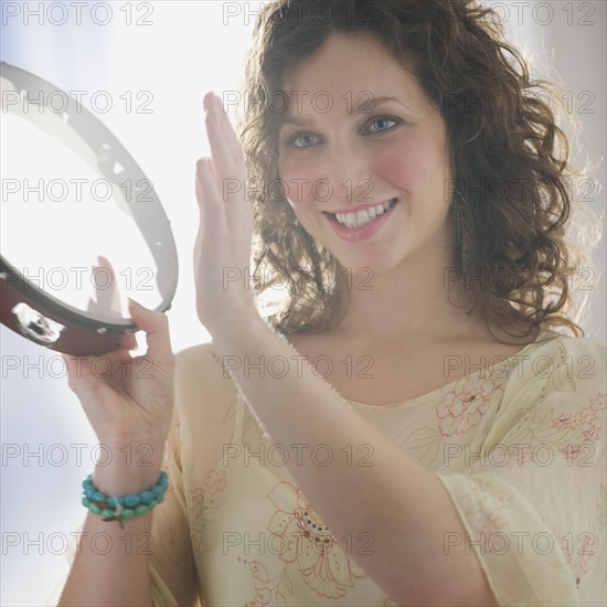 Close up of woman playing tambourine.