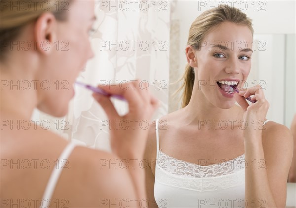 Woman brushing teeth in bathroom.