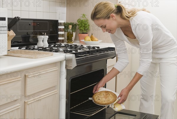 Woman removing pie from oven.