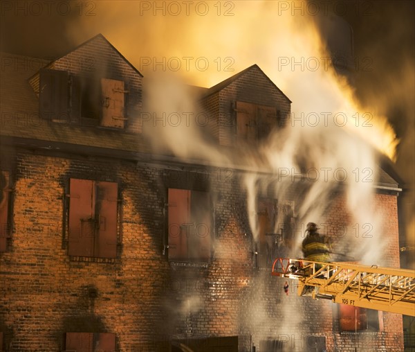 Firefighter on crane fighting building fire. Date: 2008