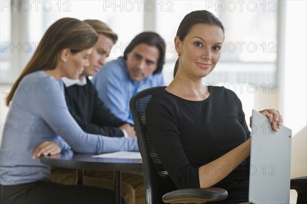 Portrait of businesswoman with business people in background.