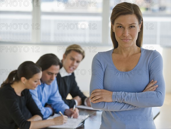 Portrait of businesswoman with business people in background.