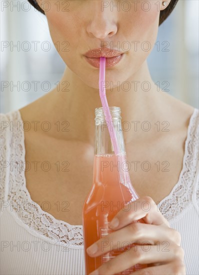 Close up of woman drinking soda from a straw.