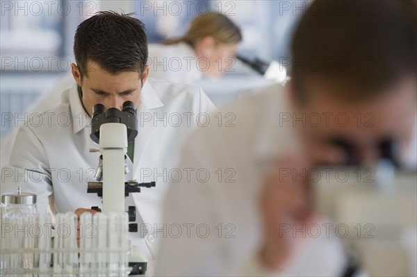 Scientists using microscopes in pharmaceutical laboratory.