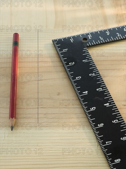 Pencil and carpenter’s rule on wood plank.