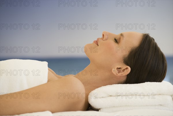 Woman laying on massage table with ocean in background.