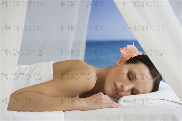 Woman laying on massage table with ocean in background.