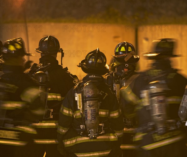 Firefighters standing outside burning building. Date: 2008