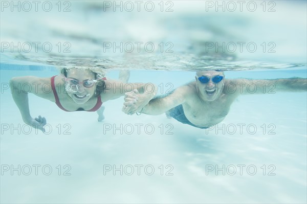 Couple swimming underwater and holding hands. Date: 2008
