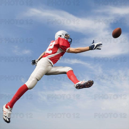 Football player in mid-air reaching for football. Date : 2008