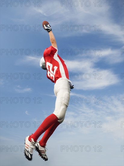 Football player in mid-air reaching for football. Date : 2008