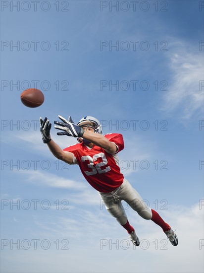 Football player in mid-air reaching for football. Date : 2008