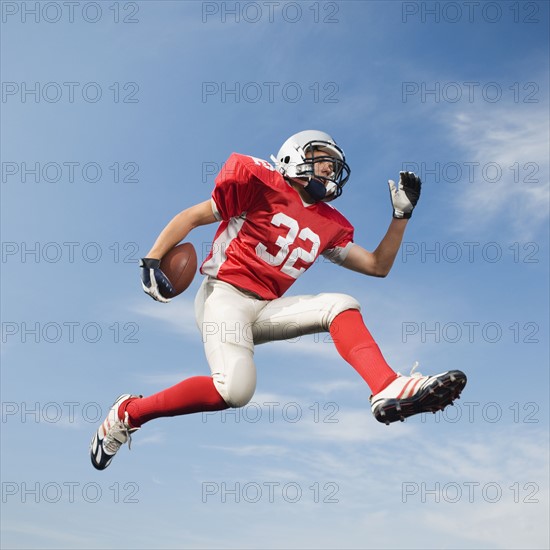 Football player in mid-air holding football. Date : 2008