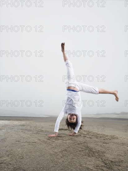 Portrait of girl doing handstand on beach. Date : 2008
