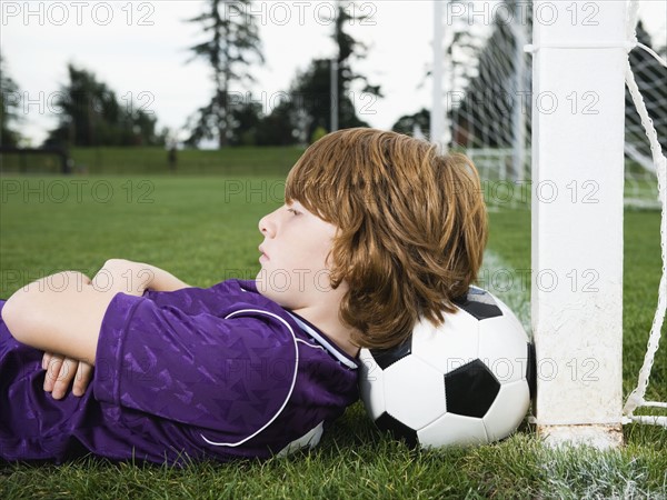 Boy laying on soccer ball against goal. Date: 2008