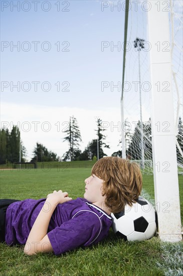 Boy laying on soccer ball against goal. Date : 2008