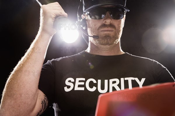 Bouncer looking at guest list with flashlight. Date : 2008