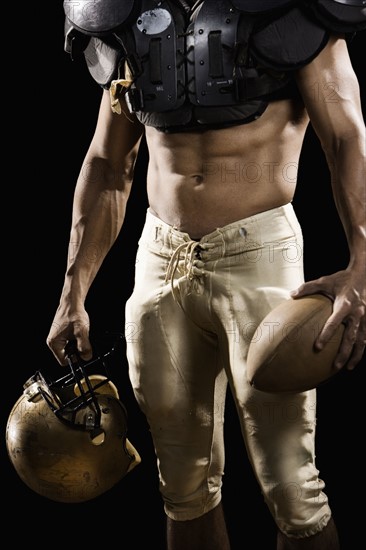 Football player with protective gear, football, and helmet. Date : 2008