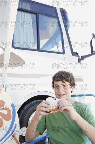 Portrait of boy eating sandwich outside motor home. Date : 2008