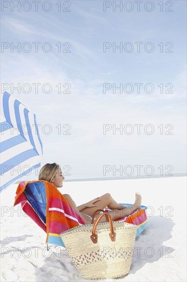 Teenage girl sunbathing on beach. Date : 2008