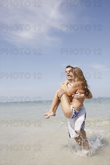 Man carrying girlfriend in ocean surf. Date: 2008