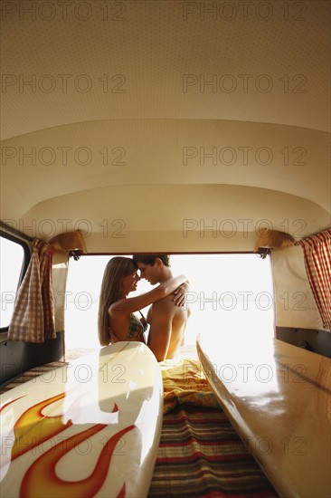 Teenage couple hugging at back of van. Date : 2008