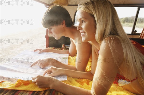 Couple laying in van and looking at map. Date : 2008