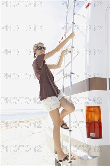 Portrait of woman standing on back ladder of motor home. Date : 2008