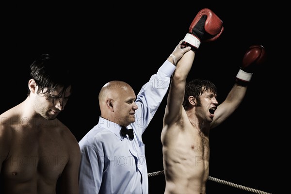 Referee standing between winning and losing boxers. Date : 2008