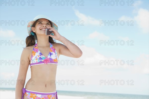 Girl in bikini talking on cell phone on beach. Date : 2008
