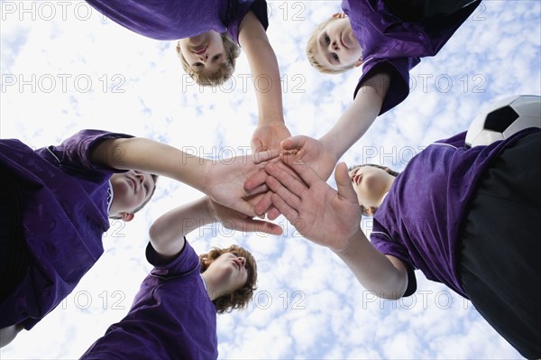 Boys touching hands in huddle. Date: 2008