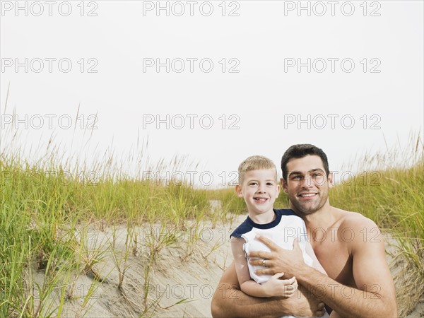 Portrait of father and son hugging on beach. Date : 2008