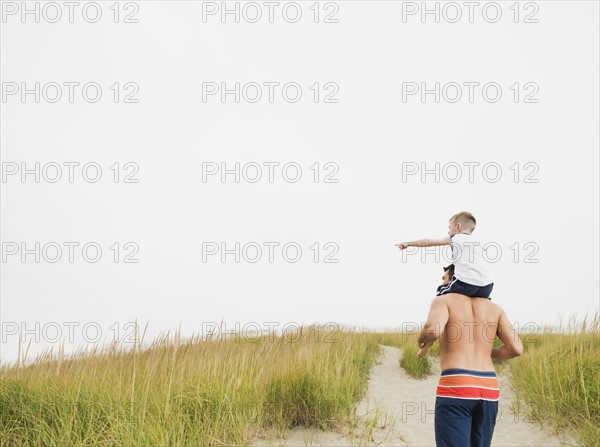 Father carrying son on shoulders at beach. Date : 2008