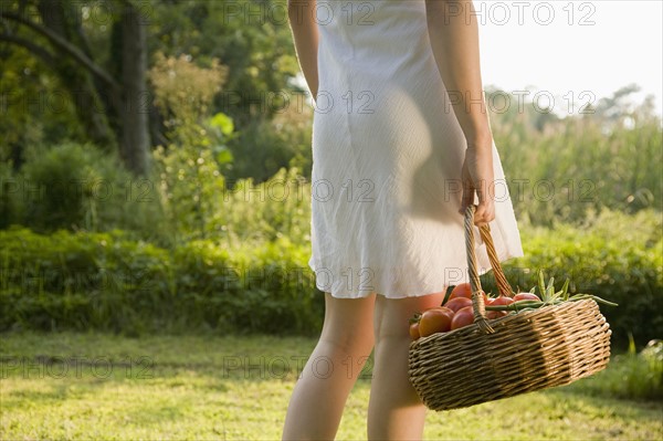 Woman carrying basket of fresh tomatoes. Date : 2008