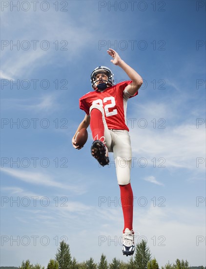 Football player in mid-air holding football. Date : 2008