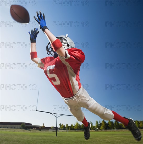 Football player in mid-air reaching for football. Date : 2008