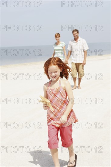 Couple and daughter walking on beach. Date : 2008