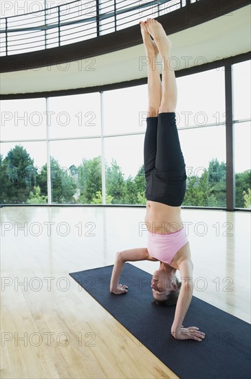 Woman doing headstand on mat. Date : 2008