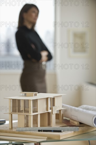 Building model and blueprints with architect in background.