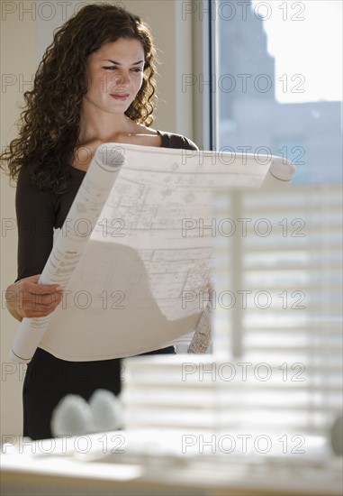 Architect viewing blueprints near building model.