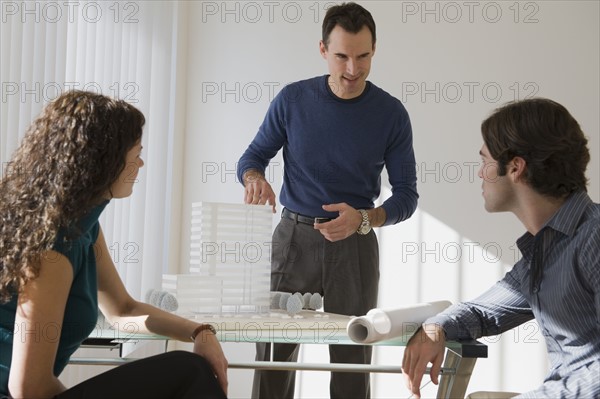 Architect presenting building model to clients.