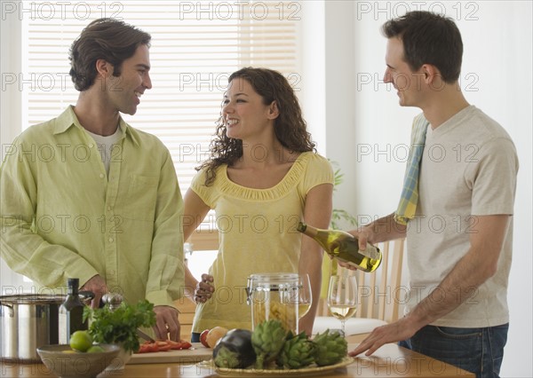 Friends preparing meal in kitchen.