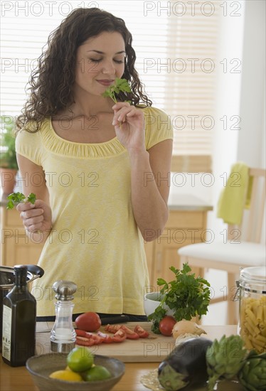 Woman smelling herbs and preparing meal.