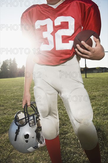 Football player holding helmet and football on field. Date : 2008
