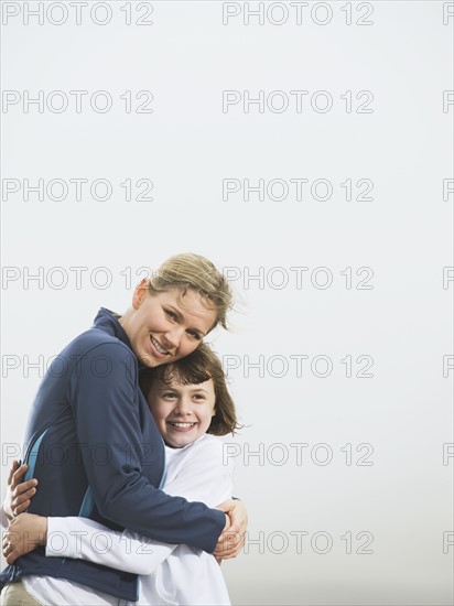 Mother and daughter hugging on beach. Date : 2008