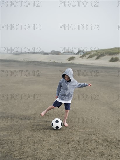 Boy kicking soccer ball on beach. Date : 2008