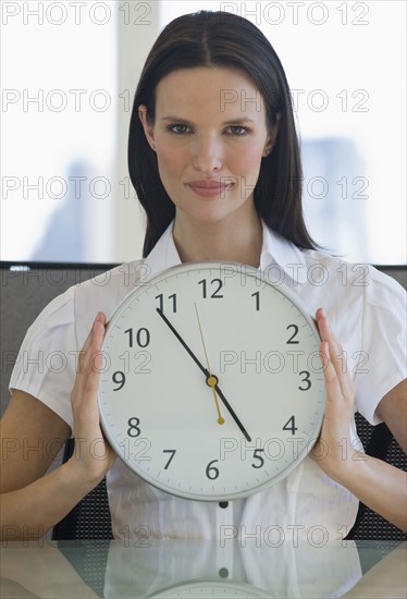 Portrait of businesswoman holding clock.