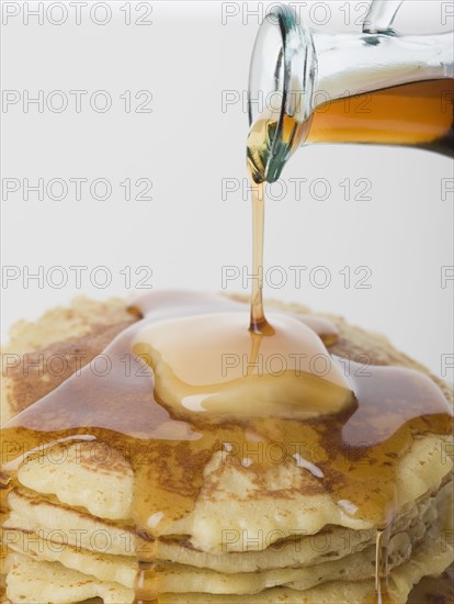 Close up of maple syrup being poured on pancakes.