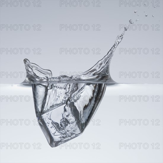 Ice cube splashing in water.